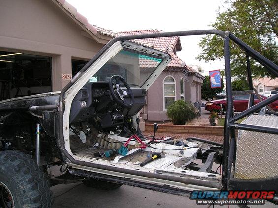 Modified truck interior with exposed floor, roll cage, and aftermarket steering wheel