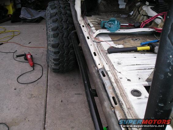 side view of a stripped-down vehicle interior with a large off-road tire and tools nearby