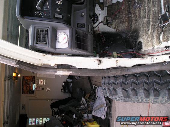 1986 Toyota Hilux interior, white exterior, showing dashboard, exposed wiring, and a large off-road tire