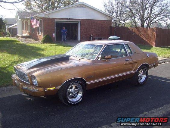 Gold 1977 Ford Mustang II coupe with black hood scoop, side view