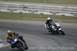 2002 Yamaha R1 - Two motorcycles lean into a turn on a race track, with a third motorcycle in the distance.