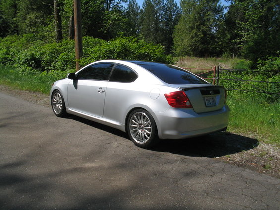 Silver 2005 Scion tC parked on asphalt road with trees and grass in background
