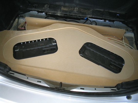 Trunk with a custom-built wooden subwoofer enclosure. Two speaker cutouts are visible