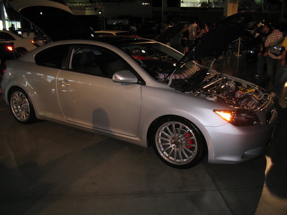 Silver 2005 Scion tC coupe with hood open, showing engine bay and red brake calipers