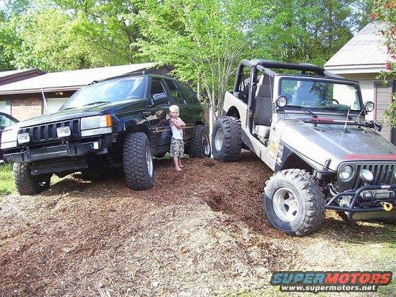 Silver Jeep Wrangler TJ with doors removed, parked next to a black Jeep Grand Cherokee