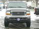 2000 Ford Excursion - A black Ford Excursion is parked outside in the snow, showing its front grille and tires.