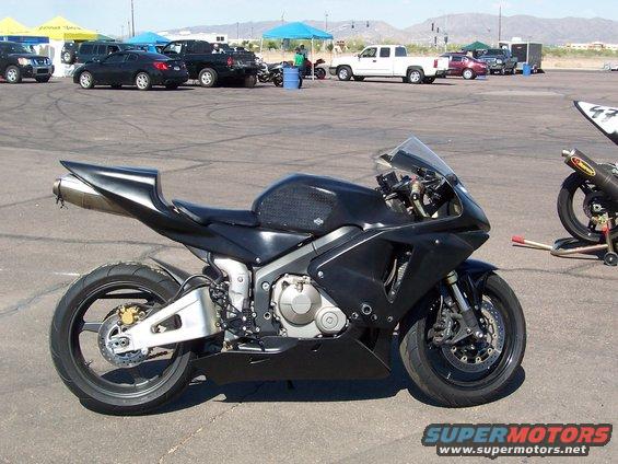 Black sport motorcycle parked on asphalt, another motorcycle on a stand in the background
