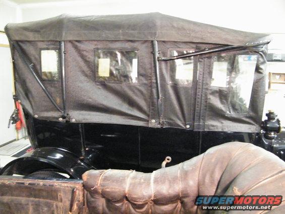 Side view of a black touring car with a fabric top and windows. The front passenger seat is visible