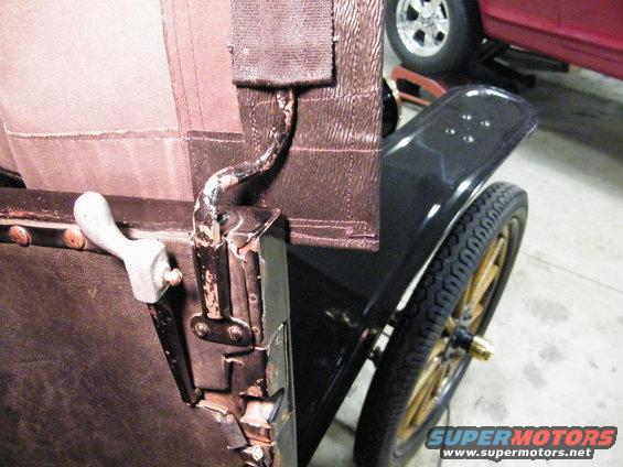 1915 Ford Model T interior with leather seat and white door handle, black fender, and gold spoked wheel