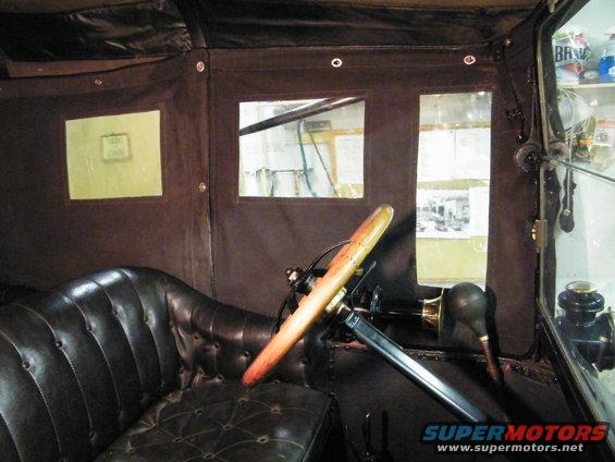 Interior of a 1915 Ford Model T showing tufted leather seats and wooden steering wheel