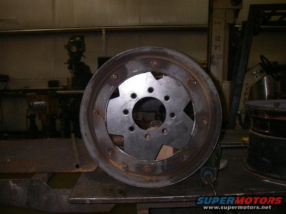Custom wheel rim with a metal plate bolted inside, sitting on a workbench