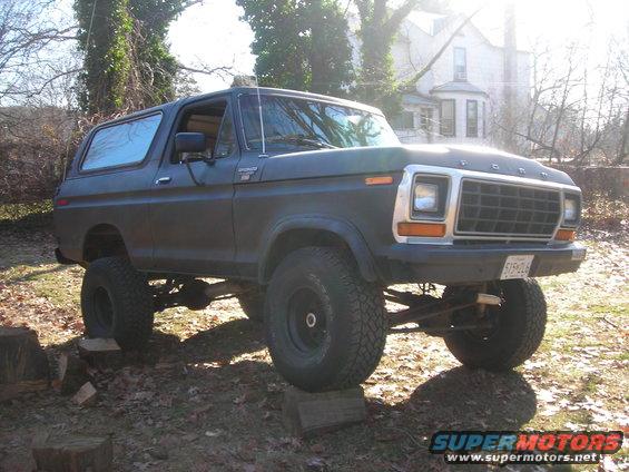 Dark gray 1978 Ford Bronco lifted with large tires, parked outdoors on blocks