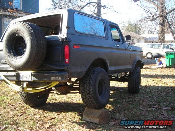 Dark gray 1978 Ford Bronco with a spare tire mounted on the rear, lifted suspension, and a yellow strap