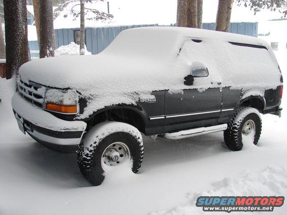 Dark 1996 Ford Bronco covered in snow, 3/4 front view