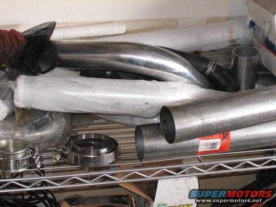 Pile of exhaust pipes and V-band clamps on a shelf