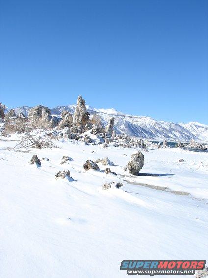 Tufa formations covered in snow with mountains in the background
