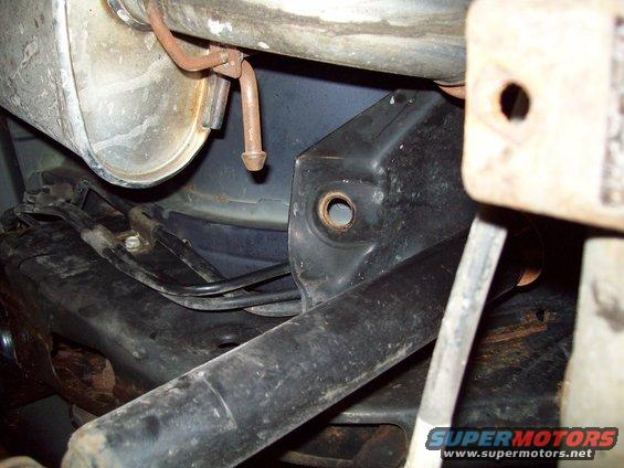 Close-up of rear suspension parts including muffler, frame, and brake lines