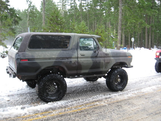 Camouflaged Ford Bronco with lifted suspension and off-road tires on a snowy road