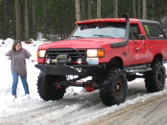 Red 1989 Ford Bronco with snorkel, winch, and lifted suspension in snow