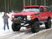 1989 Ford Bronco - A modified red 1989 Ford Bronco equipped for off-roading sits on a snowy road with a person standing nearby.