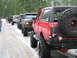 1989 Ford Bronco - A line of modified Ford Broncos are parked on a snow-covered road, with trees in the background.
