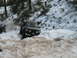 1989 Ford Bronco - An SUV navigates a snowy, wooded terrain, with another vehicle visible in the background.
