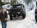 1989 Ford Bronco - A lifted black Ford Bronco navigates a snowy trail, with another vehicle visible in the background.