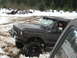 1989 Ford Bronco - Black 1989 Ford Bronco navigates a snowy and muddy trail with a driver inside.