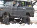 1989 Ford Bronco - A driver navigates a muddy, snow-covered terrain in a lifted off-road vehicle.