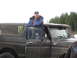 1989 Ford Bronco - A man leans out the driver's door of a black Ford Bronco, which has a Monster Energy sticker on the rear window.