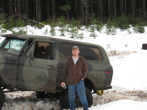 Man stands next to a camouflaged Ford Bronco with large tires in the snow