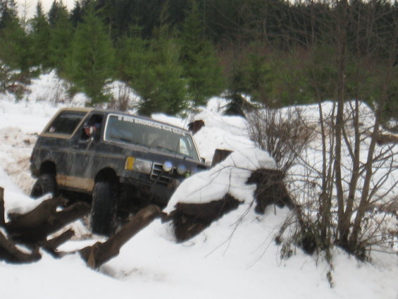 1989 Ford Bronco driving through snow with trees in background. Text on windshield reads '2 BIG BRONCOS 4X4 CLUB'