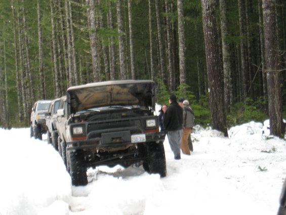 Brown Ford Bronco with hood open in snow, front view. License plate visible