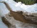 1989 Ford Bronco - A muddy track with tire ruts cuts through snow, leading to a muddy puddle.