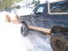 1989 Ford Bronco - Ford Bronco navigates a snowy trail with large tires and lifted suspension.