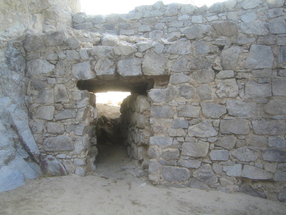 Stone ruins with a small opening leading into darkness