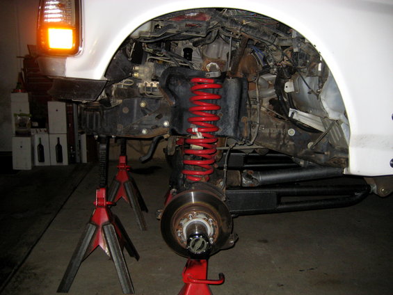 Front suspension with red coil spring, brake rotor, and hub assembly