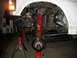 1996 Ford Bronco - Front suspension components, including a red coil spring and brake assembly, are visible with the vehicle supported by jack stands.