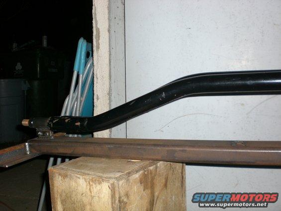 Black metal bar attached to a metal frame on a wooden block