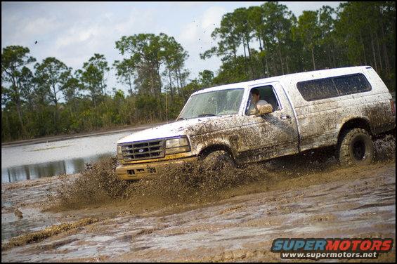 White 1996 Ford F-150 splashing through mud
