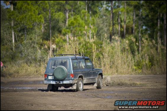 Mitsubishi Pajero driving on dirt road, spare tire on rear door