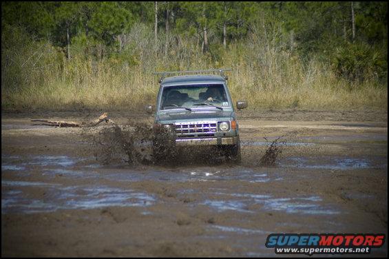 Mitsubishi Montero driving through mud, kicking up water