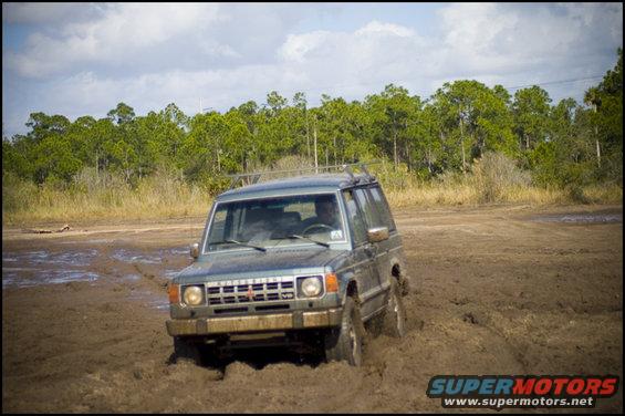 Gray SUV with a roof rack stuck in deep mud, front view