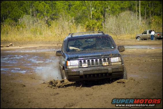Jeep Grand Cherokee stuck in mud, another truck in background