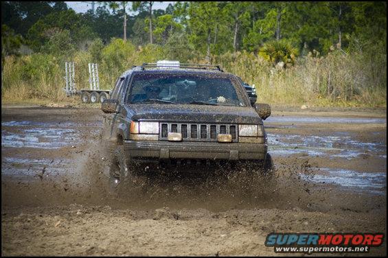 Jeep Grand Cherokee driving through mud, kicking up water
