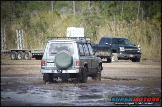 Mitsubishi Pajero and Chevrolet Silverado driving through mud puddle