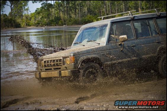 Dark green SUV splashing mud while driving through water