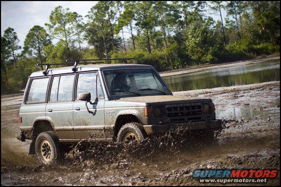 Light-colored SUV splashing through mud, front grille visible