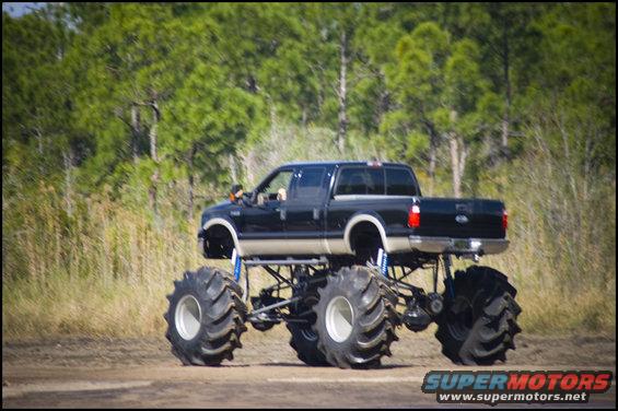 Black and tan monster truck with large tires and lifted suspension, seen from the side