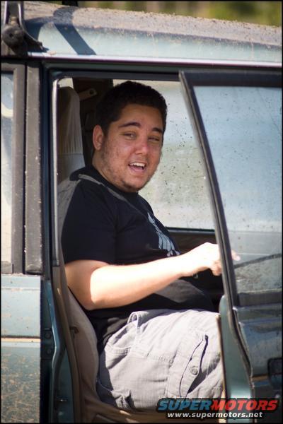 Man smiling in the driver's seat of a dark green vehicle
